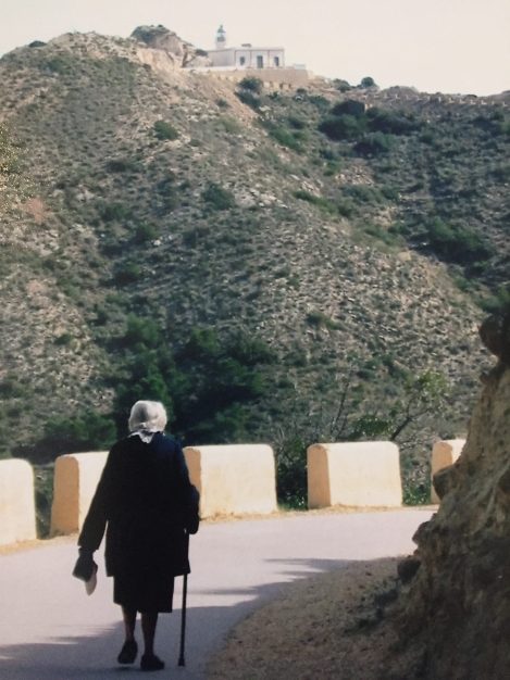 A Spanish woman walks to a lighthouse on the Mediterranean coast of Spain.